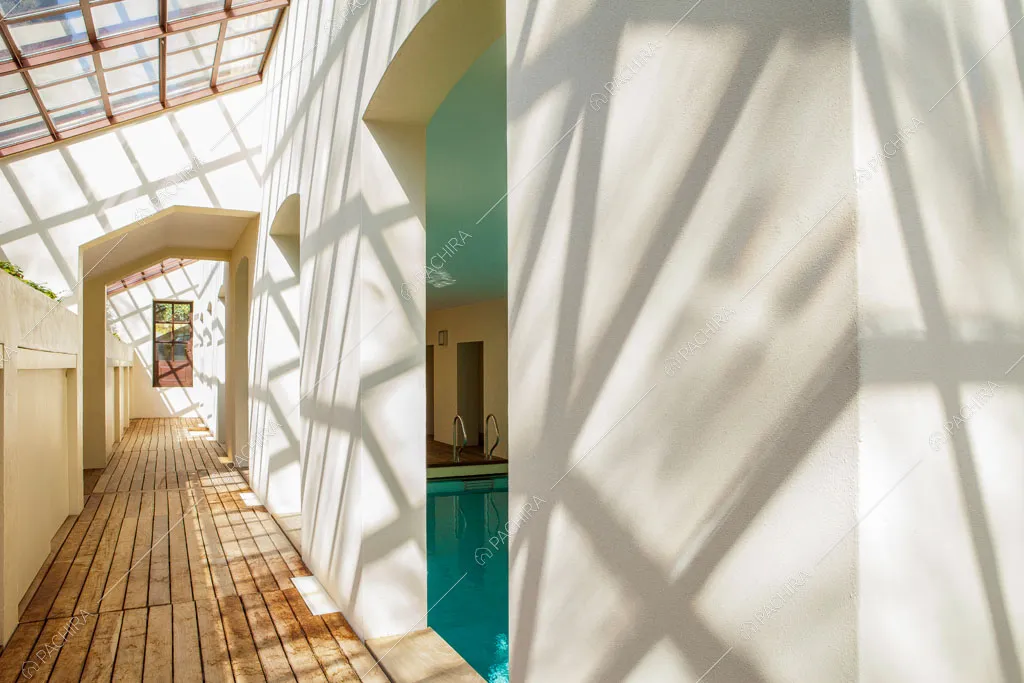 Corridoio riempito di luce naturale dai lucernari, pavimento in parquet e vista sulla piscina