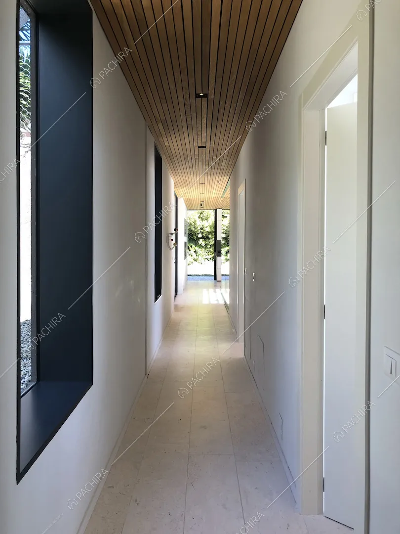 Corridoio con soffitto in legno, pareti bianche e pavimento in pietra