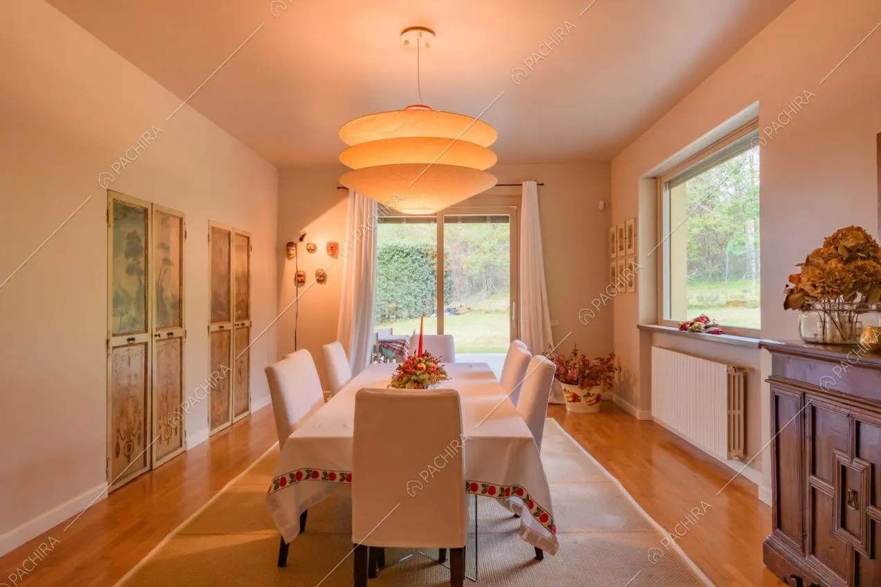 Sala da pranzo con vista sul giardino tramite le vetrate e pavimento in parquet
