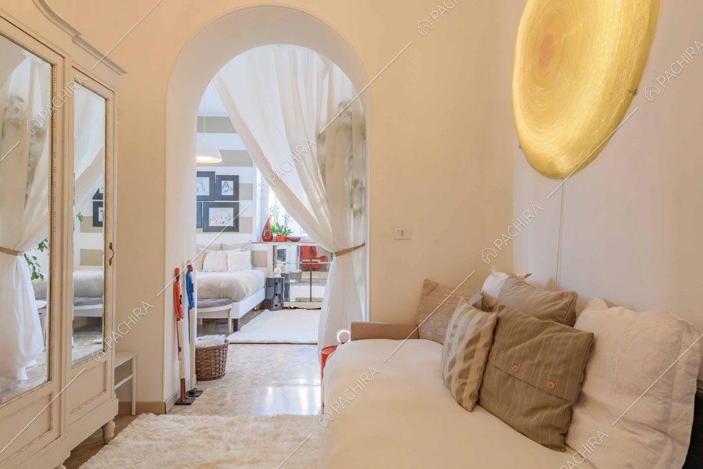 Salottino con divano bianco, volta e armadio con boiserie e specchio