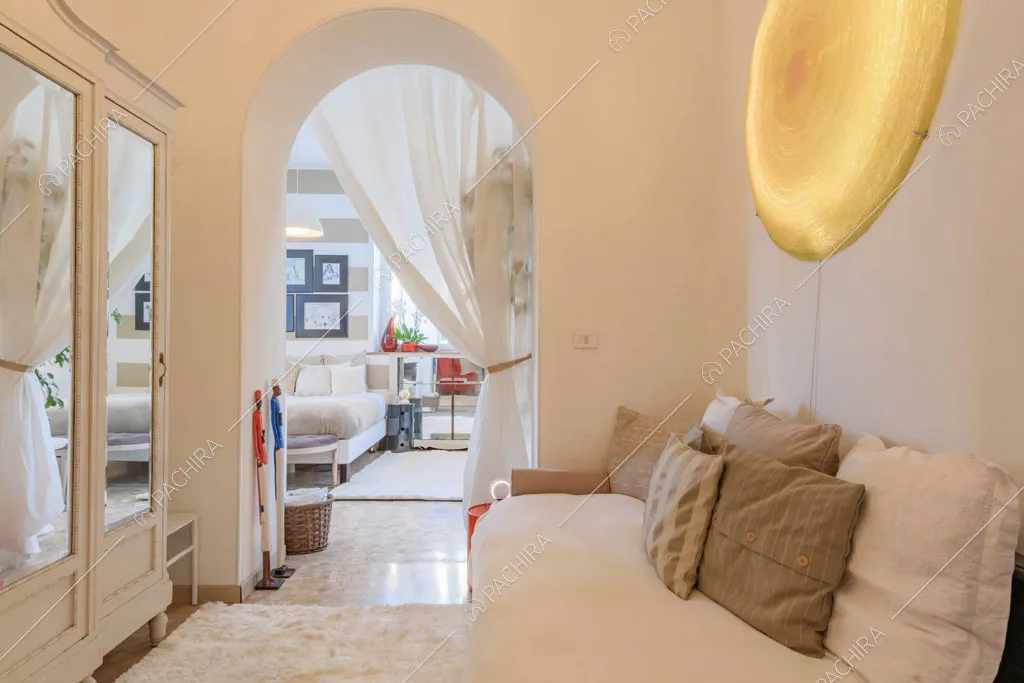 Salottino con divano bianco, volta e armadio con boiserie e specchio