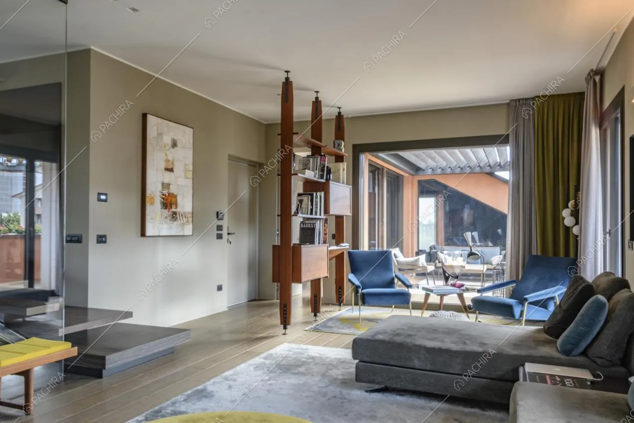Soggiorno con mobile libreria, poltrone in velluto blu e divano con chaise longue