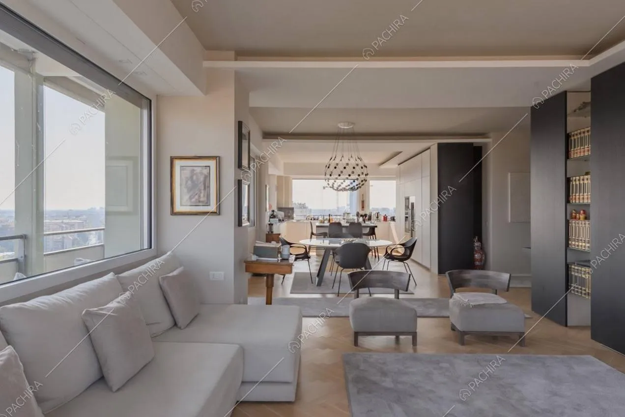 Grande zona living con divano bianco, vetrate e pavimento in parquet