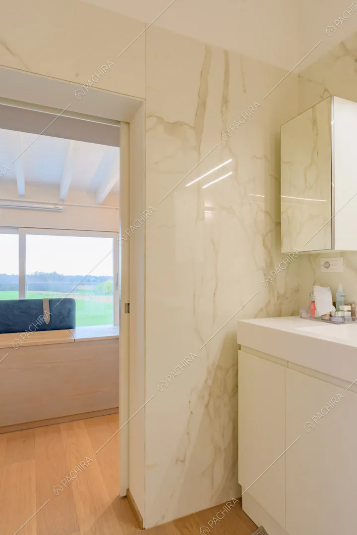 Bagno della camera da letto con pareti in marmo bianco e pavimento in parquet