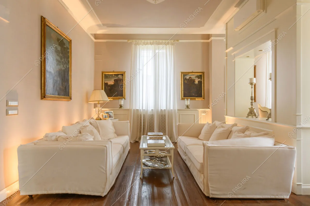 Luminoso salotto con pavimento in parquet, divani bianchi e boiserie sulle pareti