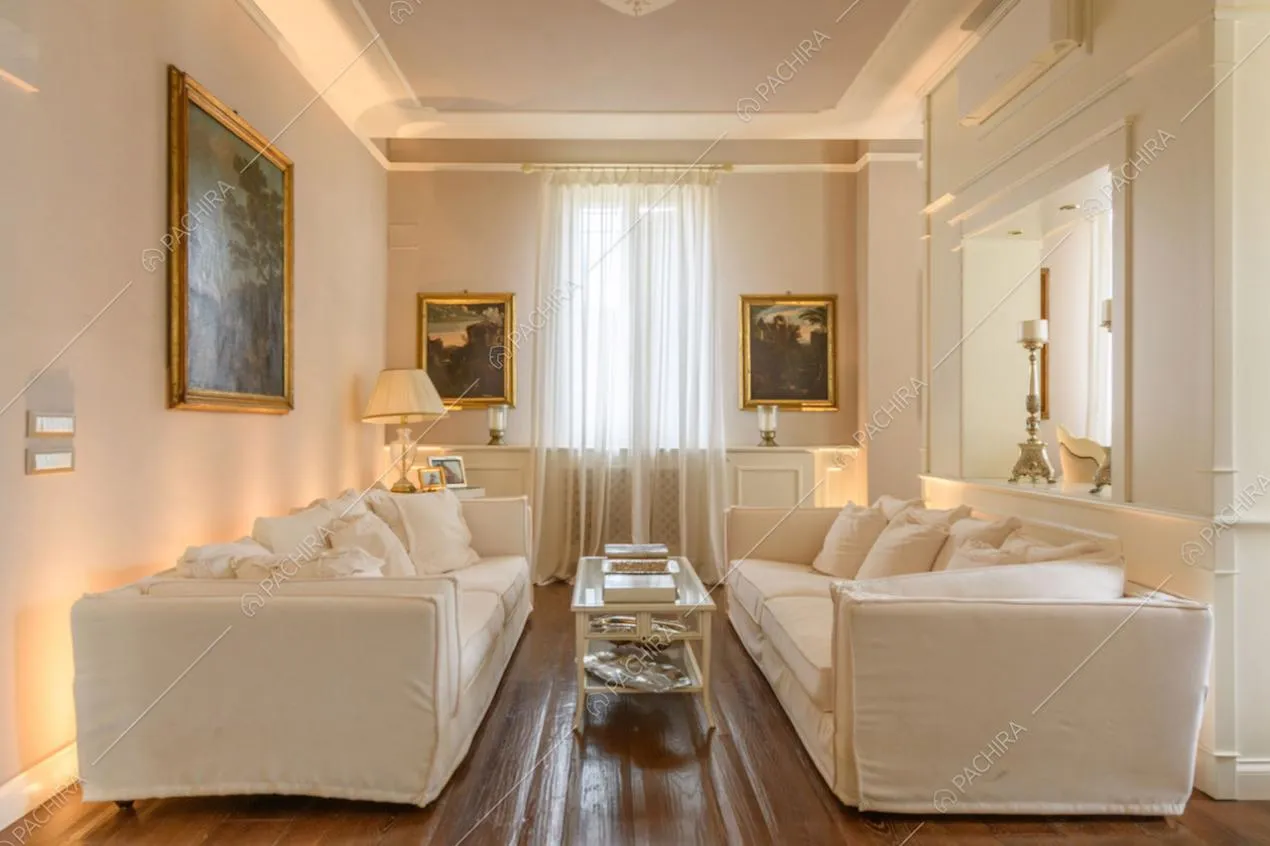 Luminoso salotto con pavimento in parquet, divani bianchi e boiserie sulle pareti