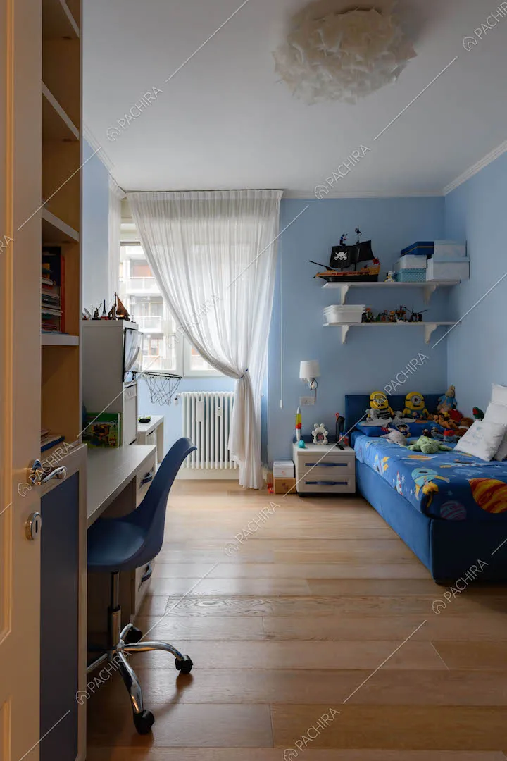 Camera da letto di un bambino con pareti azzurre, scrivania e pavimento in parquet