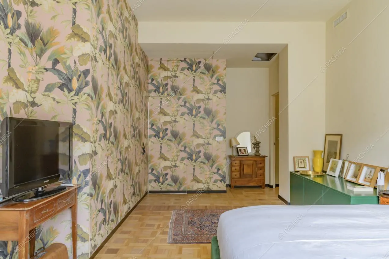 Letto matrimoniale in camera con pareti beige, carta da parati e pavimento in parquet