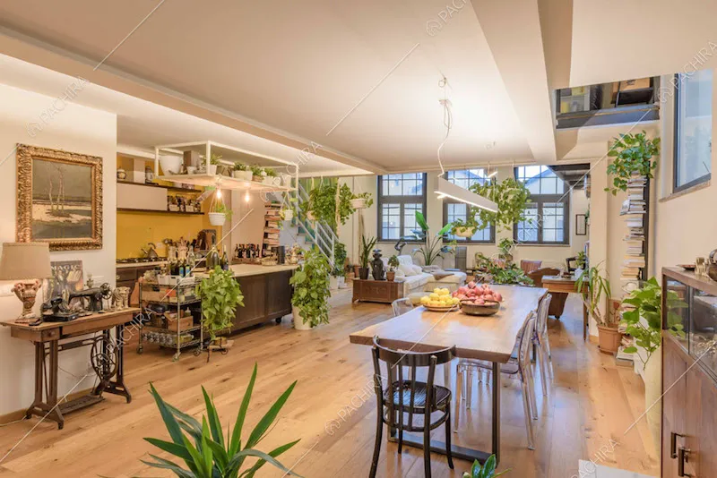 Tavolo da pranzo nella zona living con vista sulla cucina con isola e fornelli a gas