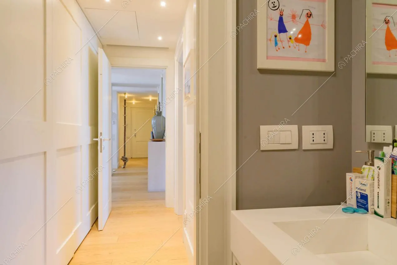 Bagno con parete grigia, pavimento in parquet e vista sul corridoio