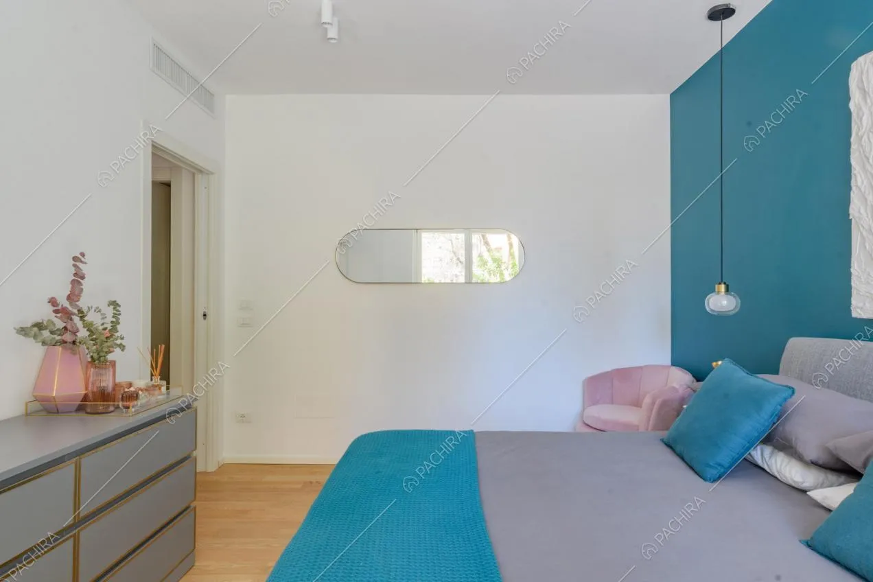 Luminosa camera da letto con pavimento in parquet, pareti bianche e azzurra
