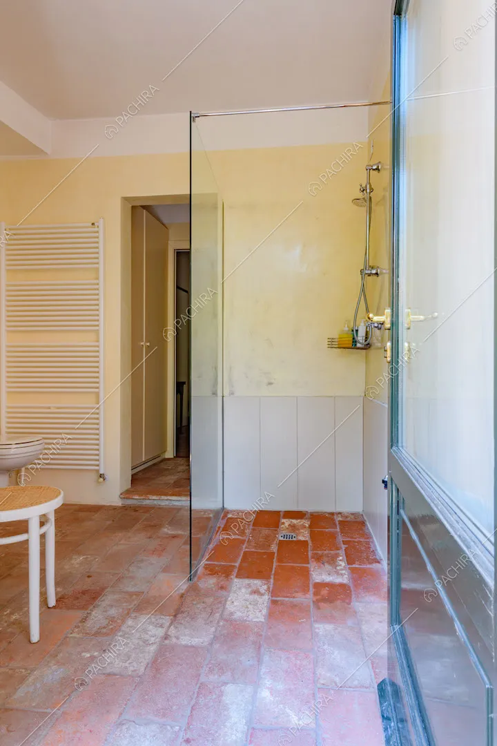 Bagno con pavimento in cotto, pareti gialle e box doccia