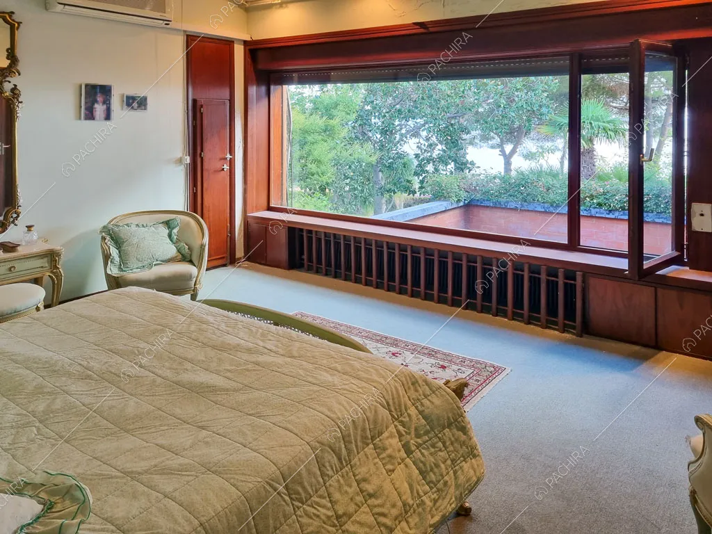 Camera da letto matrimoniale con pareti bianche e grande vetrata con vista sul giardino