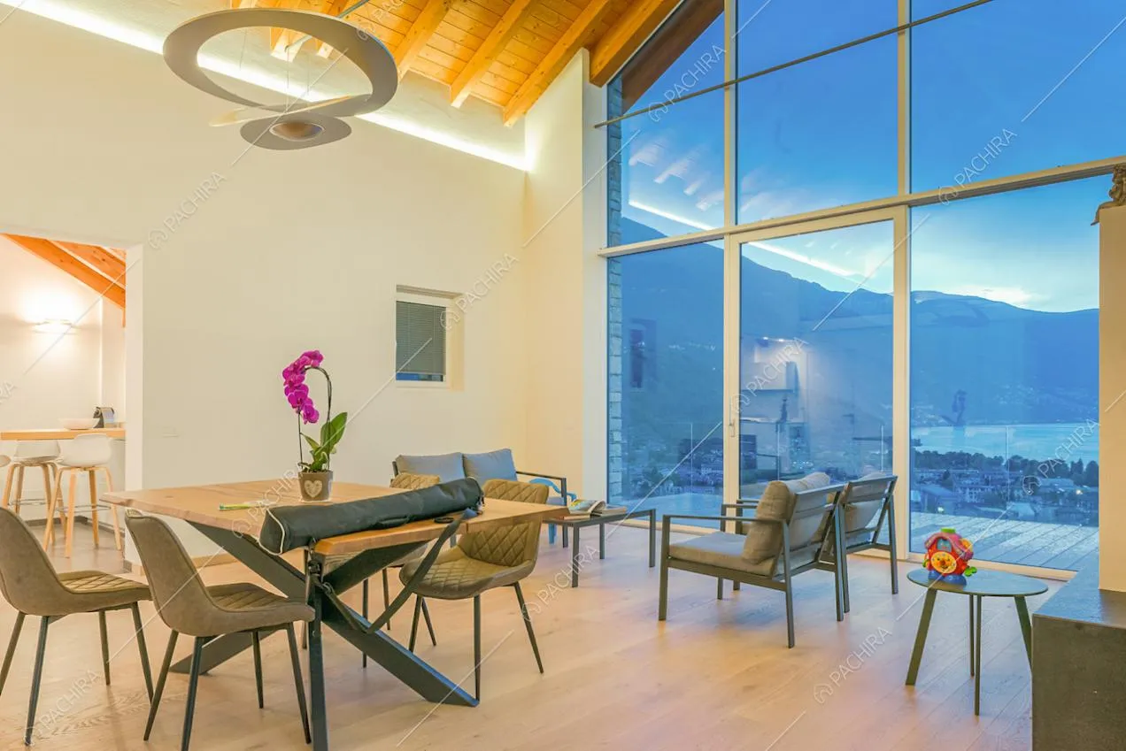 Soggiorno con lampadario di design, ampia vetrata con porta-finestra per accedere alla terrazza vista lago