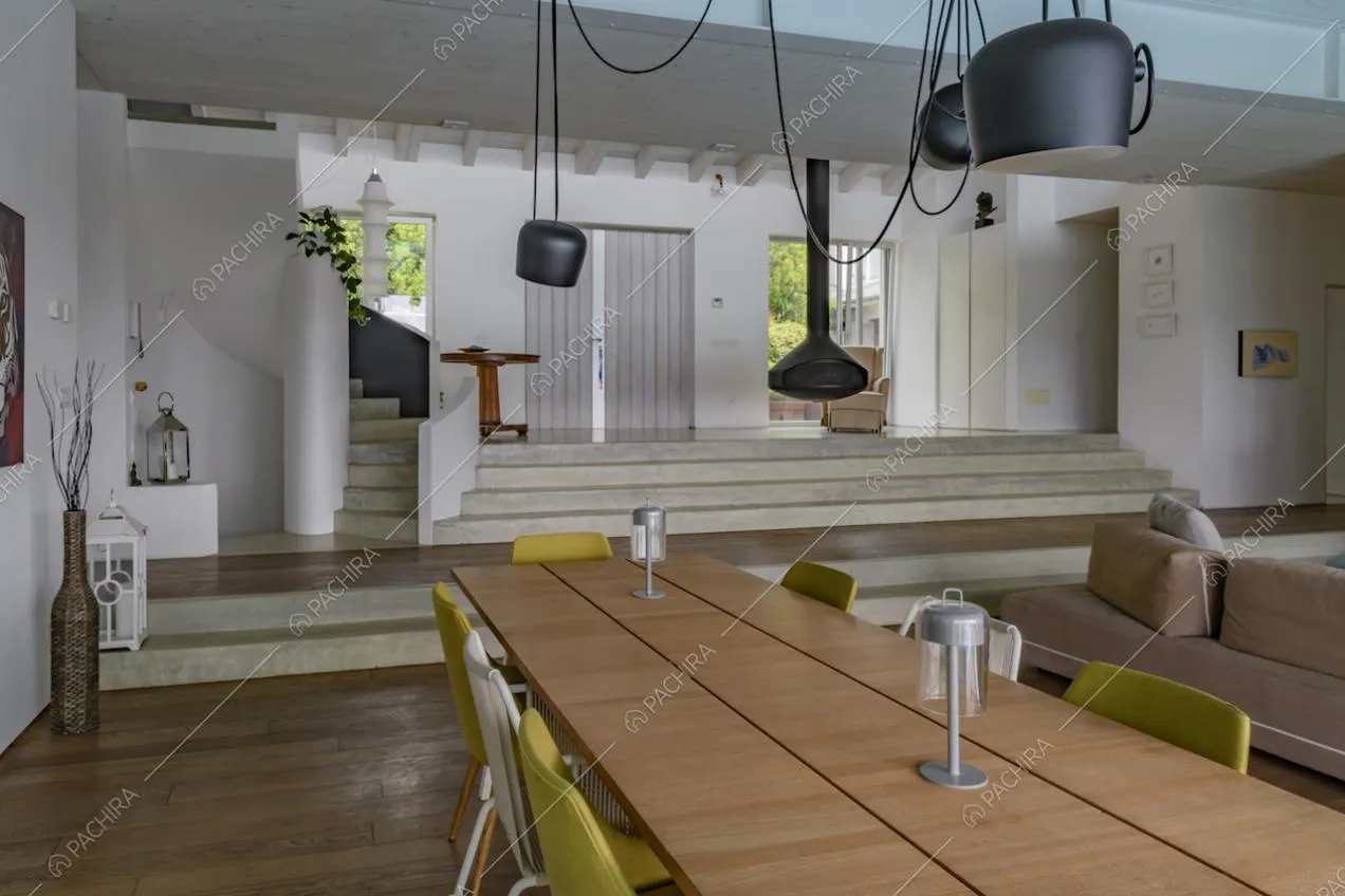 Tavolo da pranzo in legno con lampade di design nella sala da pranzo e vista sulle scale