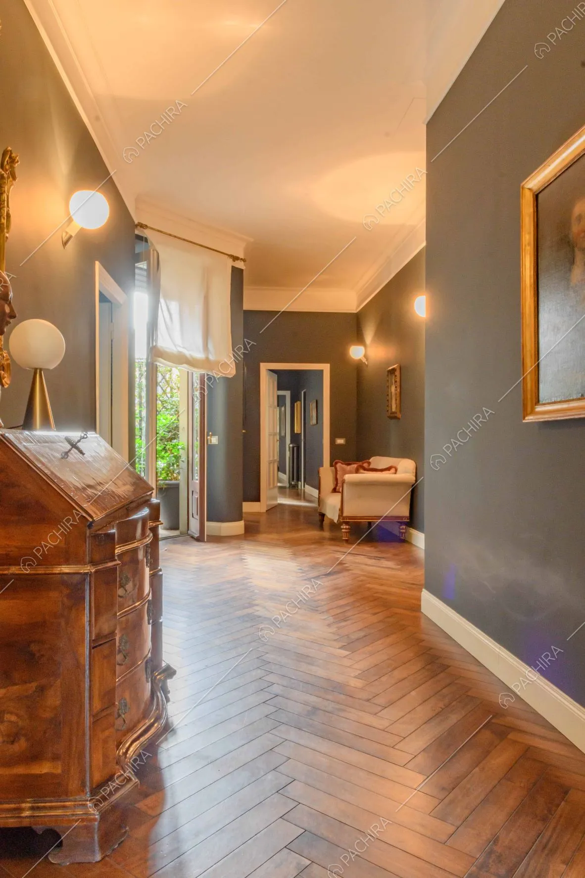 Lungo corridoio dalle pareti blu, con pavimento in parquet e porta-finestra per accedere alla terrazza