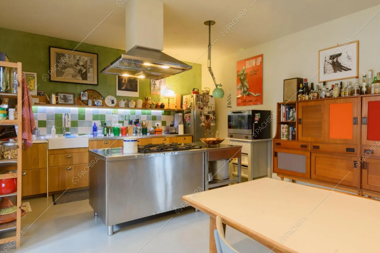 Cucina con isola in acciaio e fornelli a gas e pavimento bianco in resina