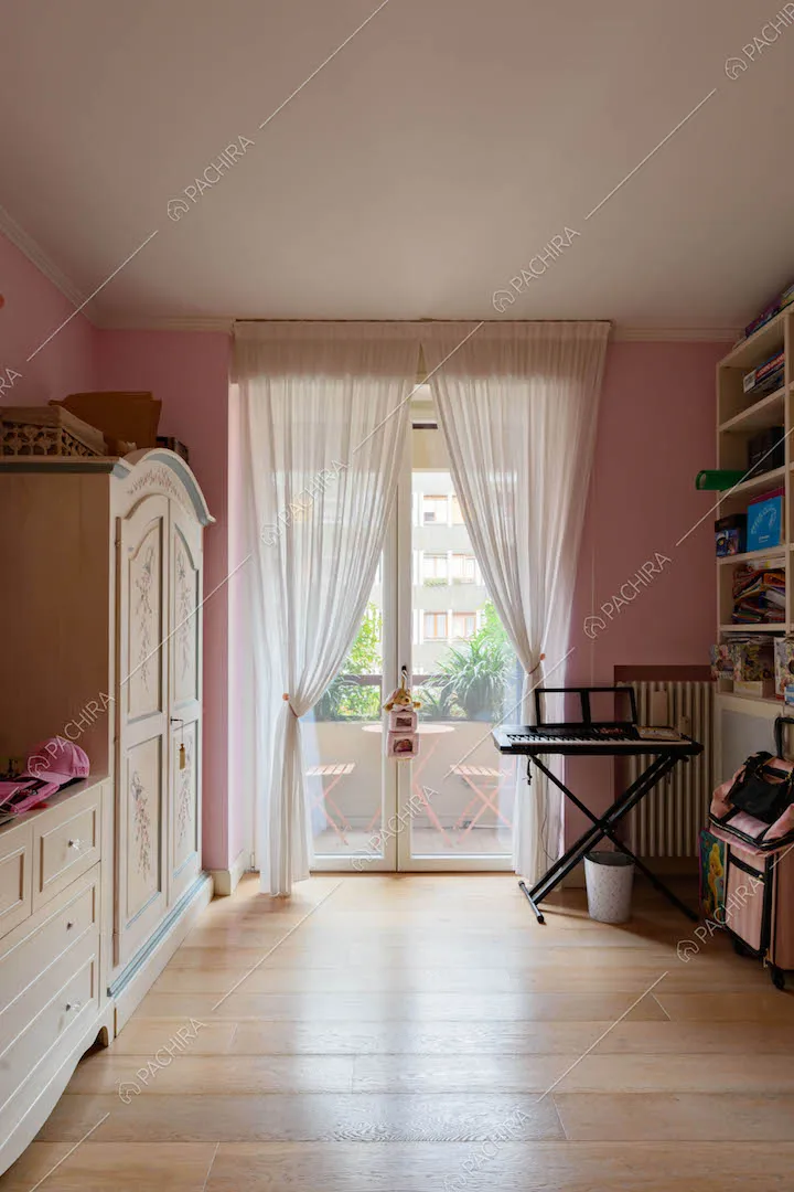 Camera da letto dei bambini con pareti rosa, pavimento in parquet e porta-finestra