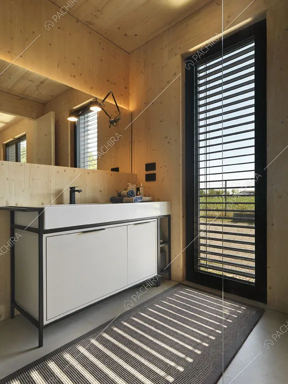 Mobile bianco nel bagno privato con vetrata e pareti e soffitto in legno