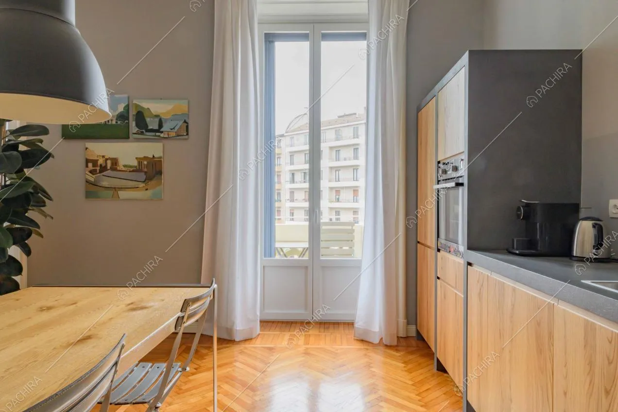 Nella cucina con pavimento in parquet a spina di pesce tavolo da pranzo in legno e lampadari di design