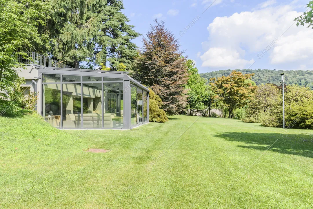 Giardino con serra arredata e alberi di diverse specie
