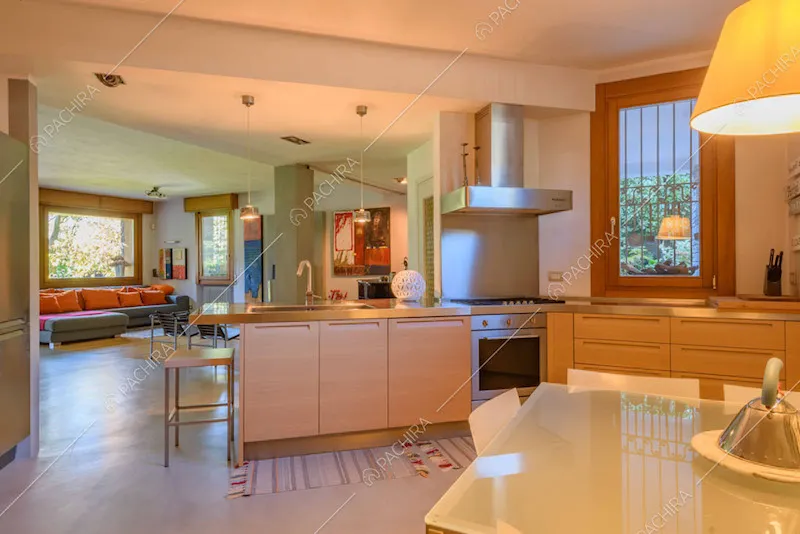 Cucina in legno con fornelli a gas e vista sulla zona living con divano angolare