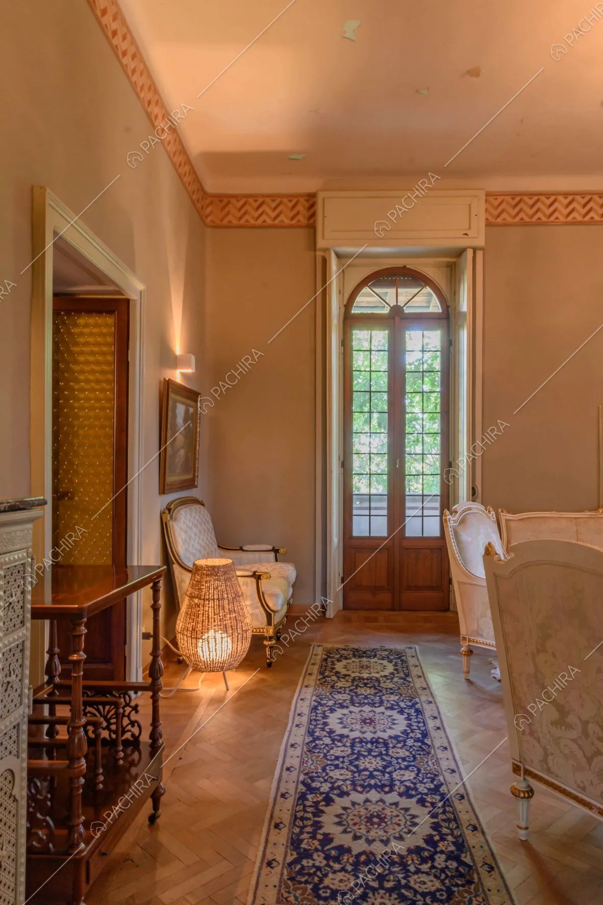Salotto con pavimento in parquet a spina di pesce, illuminato dalla porta-finestra