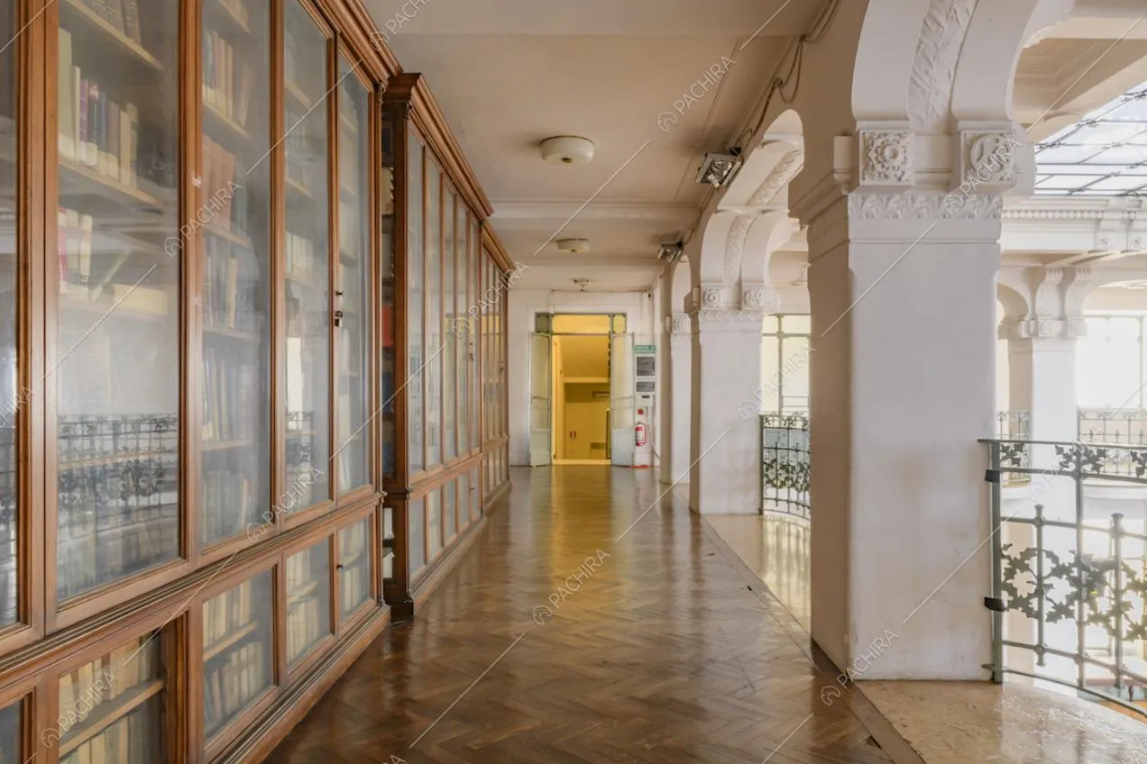 Balconata con pavimento in parquet a spina di pesce, librerie in vetro e legno e colonne bianche con boiserie