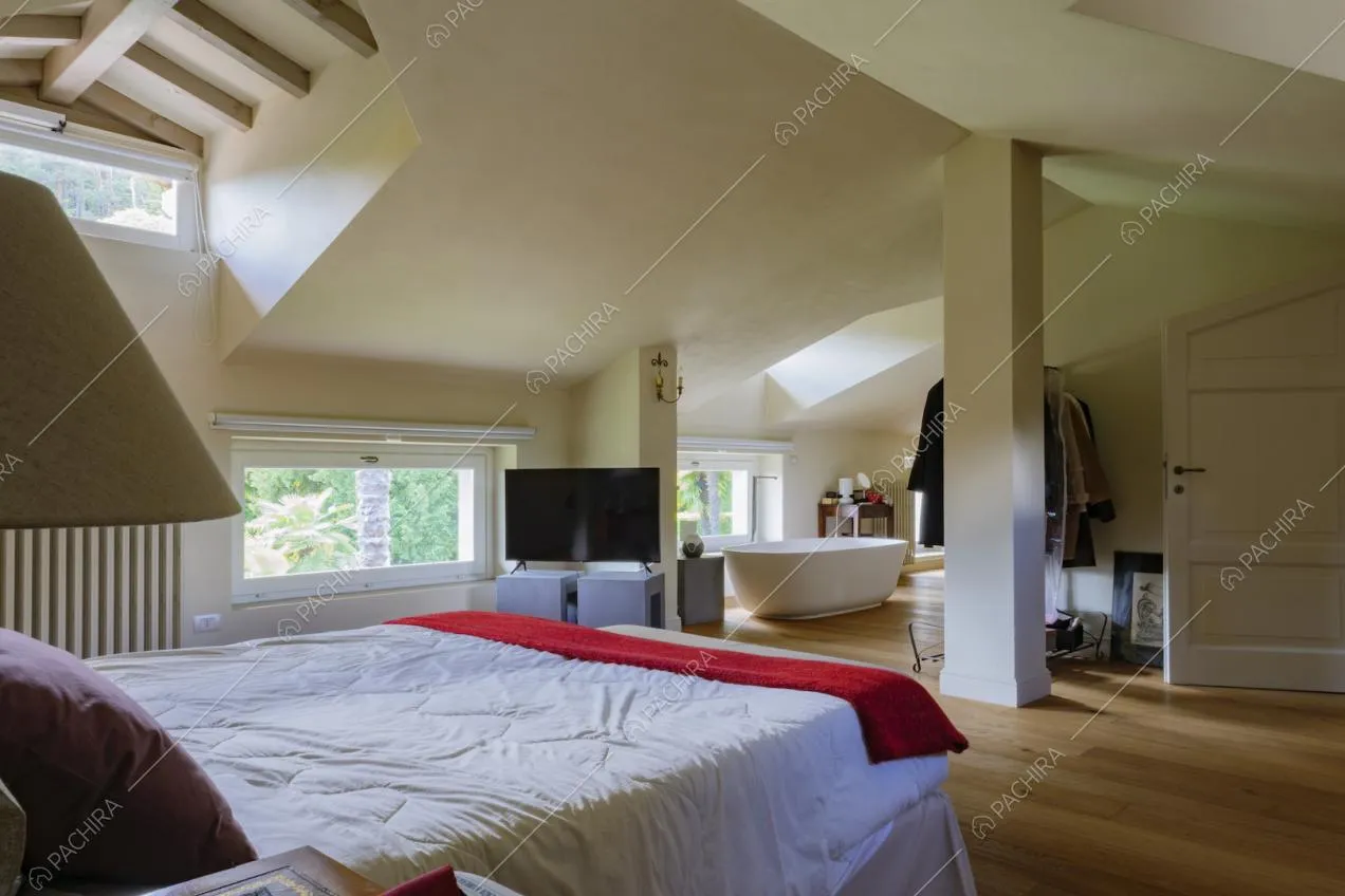 Camera da letto matrimioniale con lucernari, pavimento in parquet e vasca da bagno