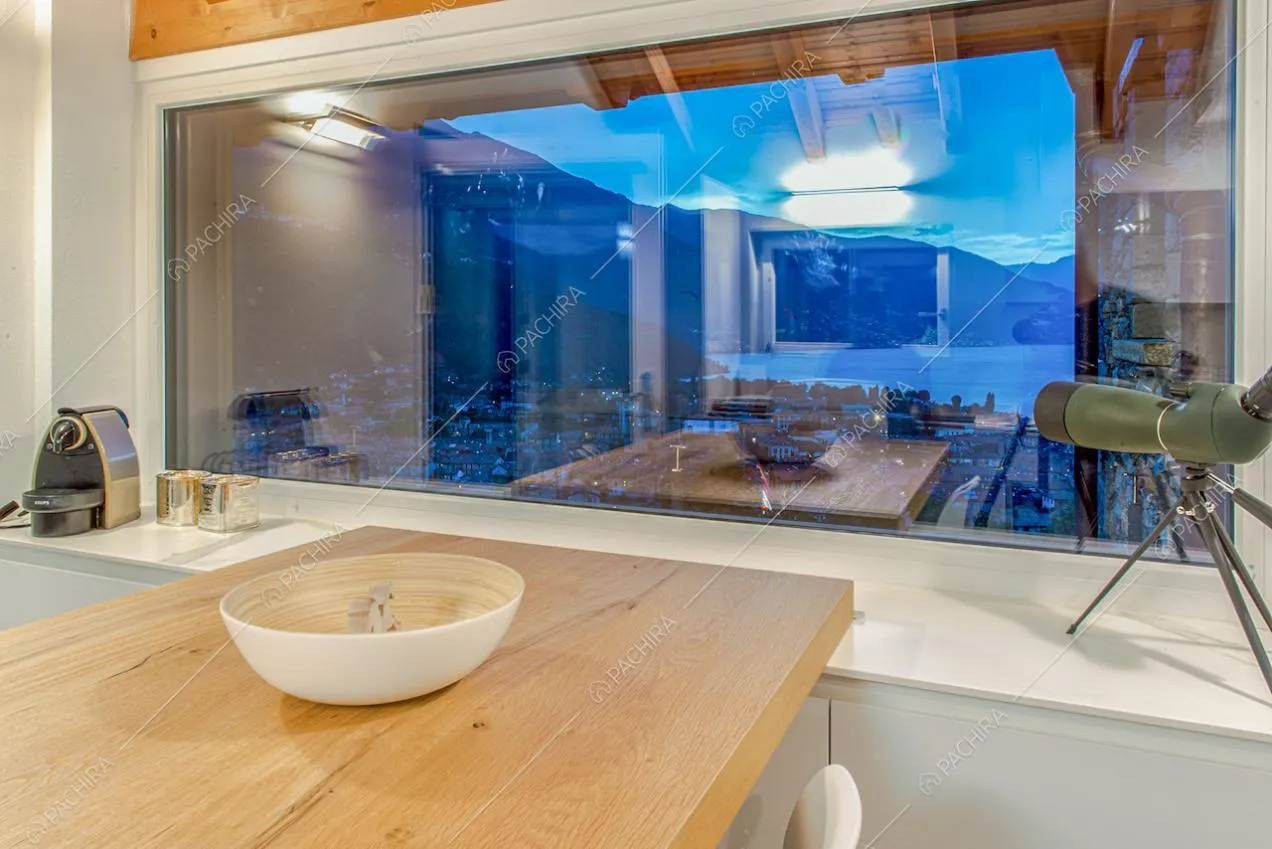 Tavolo da pranzo in legno con ampia vetrata e vista sul lago