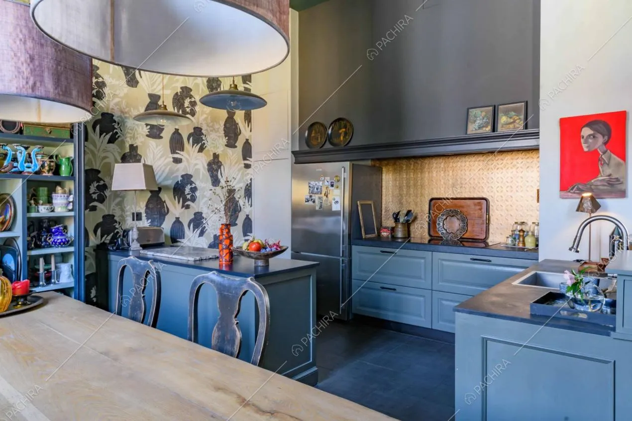 Dal tavolo da pranzo in legno vista sulla cucina con fornelli a induzione e sulla carta da parati