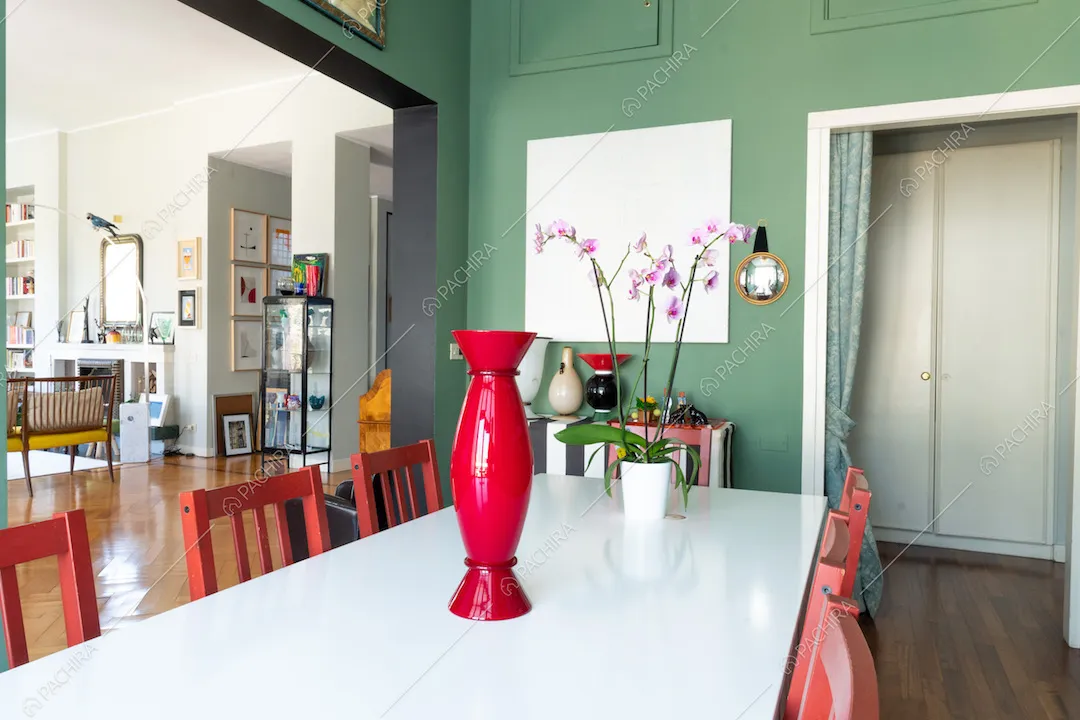 Dalla sala da pranzo vista sul salotto con pavimento in parquet a spina di pesce e camino