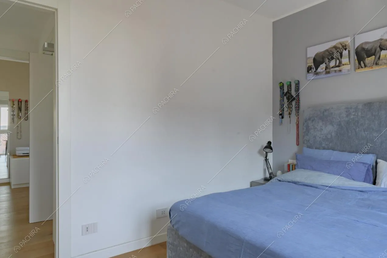 Camera da letto matrimoniale dalle pareti bianche e grigie e pavimento in parquet