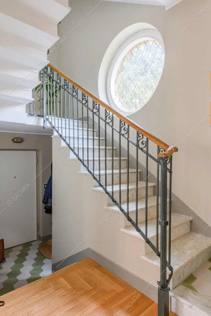 Scale in marmo, vista sull'atrio con porta d'ingresso e pavimento in cementine verdi e bianche