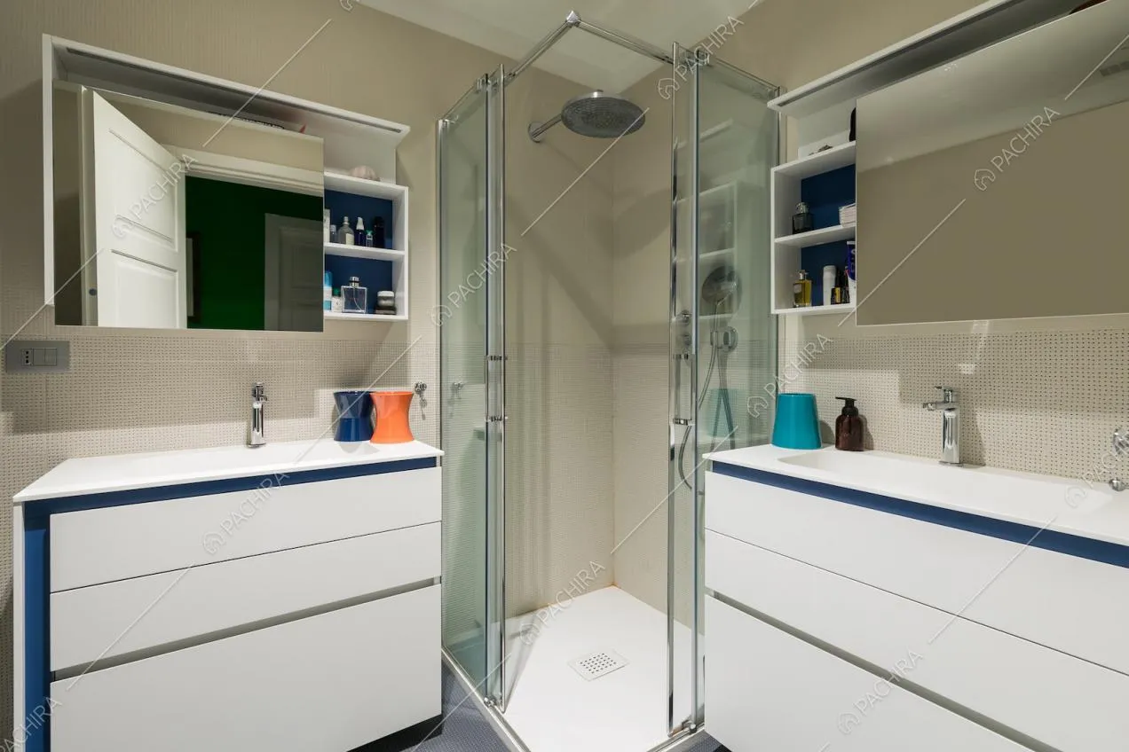 Bagno con mobili bianchi e blu, box doccia e pareti beige