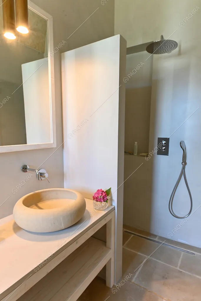 Bagno dai toni chiari, con pavimento in pietra e lampada di design