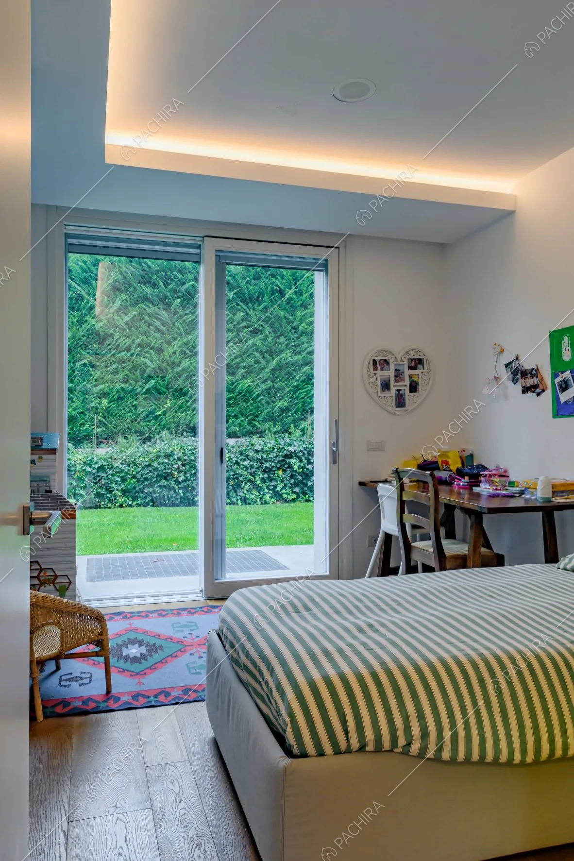 Camera da letto matrimoniale dalle pareti bianche e con porta-finestra per accedere al giardino