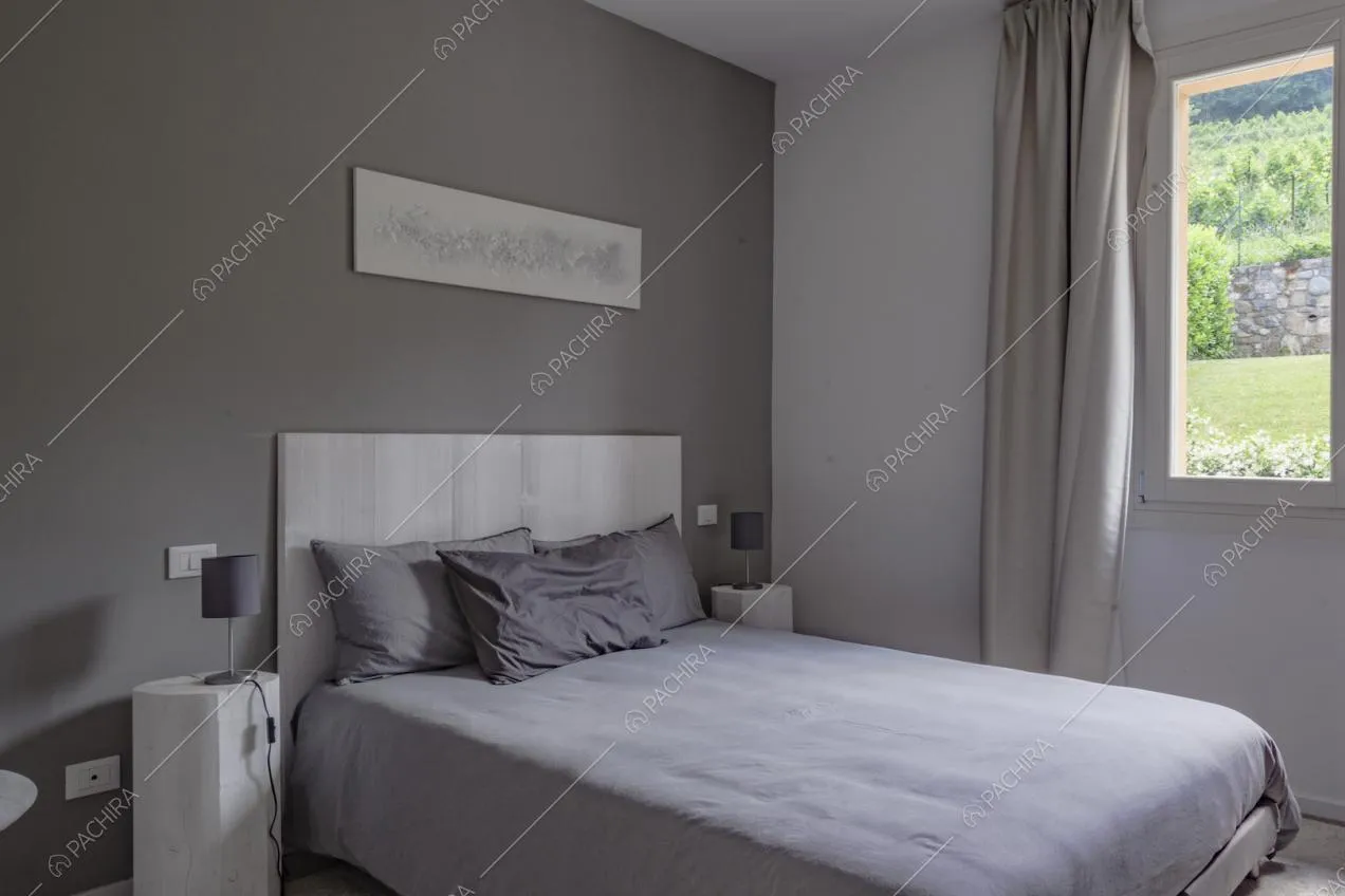 Parete color grigio e letto matrimoniale con cuscini