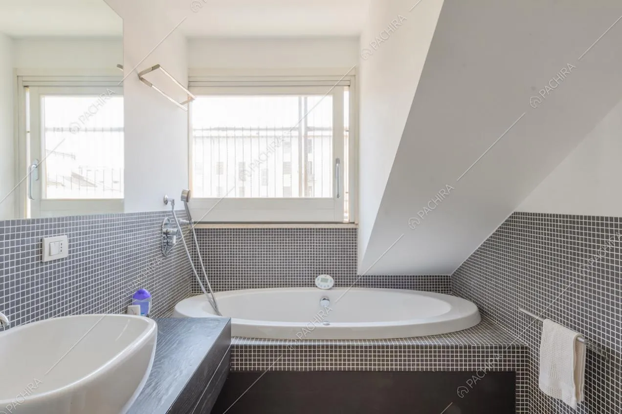 Piccole piastrelle nere sulle pareti del bagno con vasca