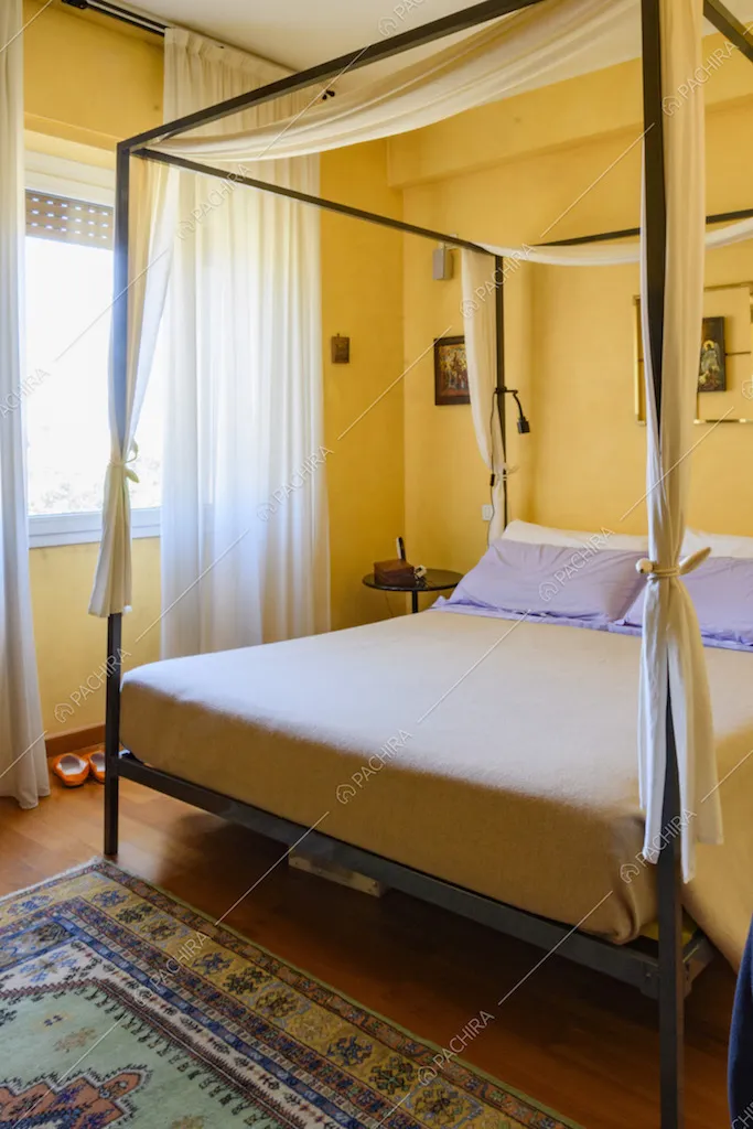 Letto a baldacchino, tende bianche e tappeto