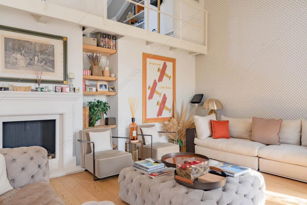 Pouf beige nella zona living con camino, pavimento in parquet e vista sul soppalco