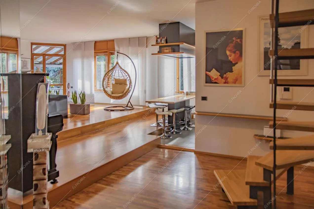 Pavimento in parquet nella luminosa zona living con scale che conducono al piano superiore e bancone