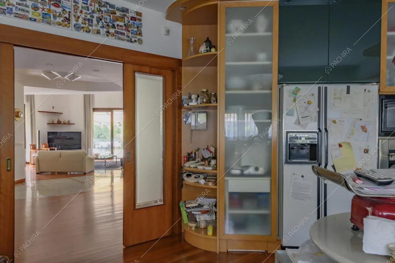 Dalla cuina vista sul salotto con pavimento in parquet attraverso la porta scorrevole aperta