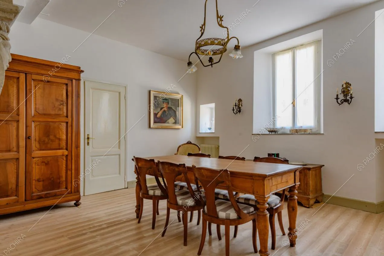 Sala da pranzo con tavolo in legno, pavimento in parquet e pareti bianche
