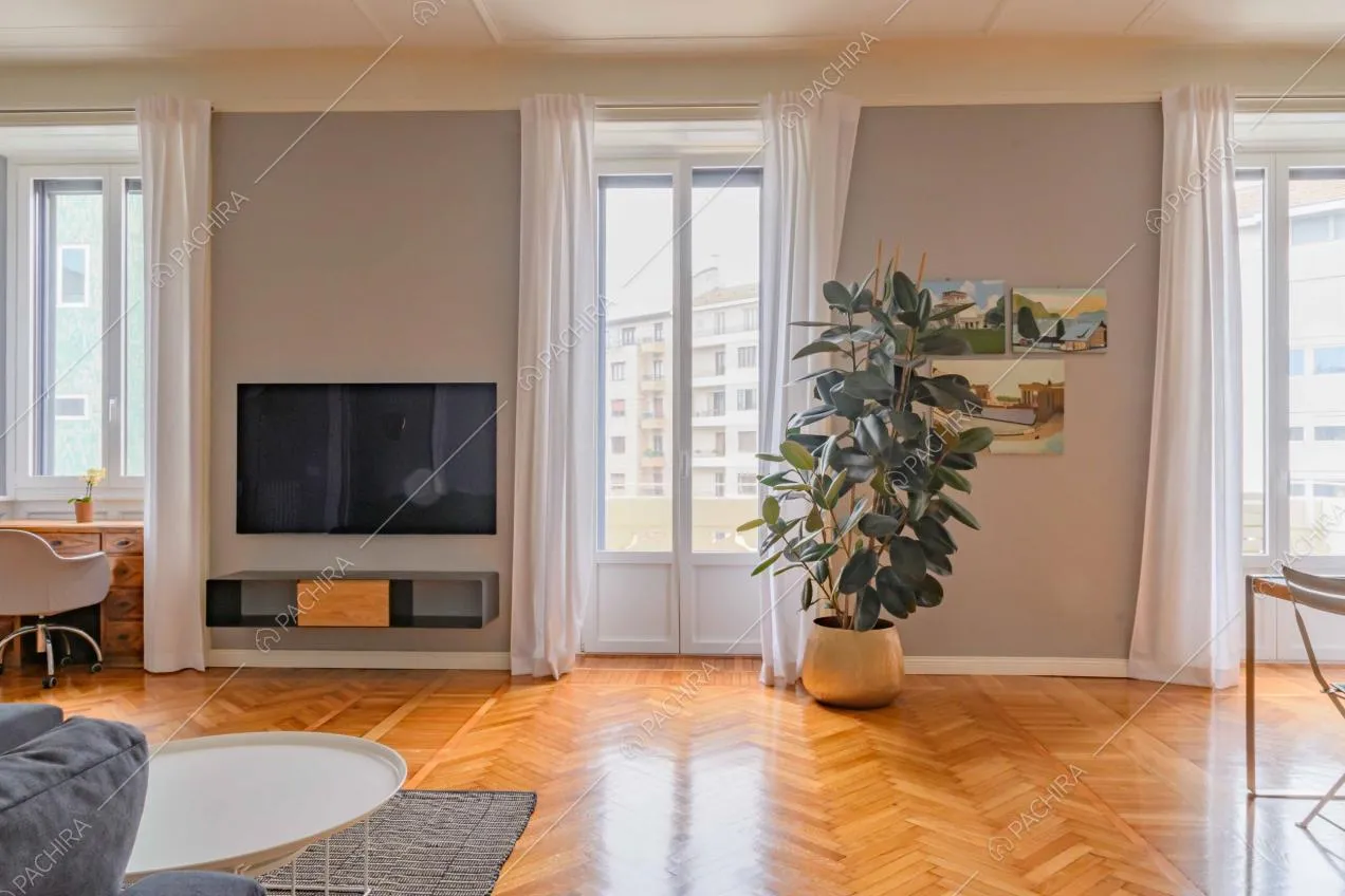 Sala con boiserie sul soffitto, porte-finestre, scrivania e pavimento in parquet a spina di pesce