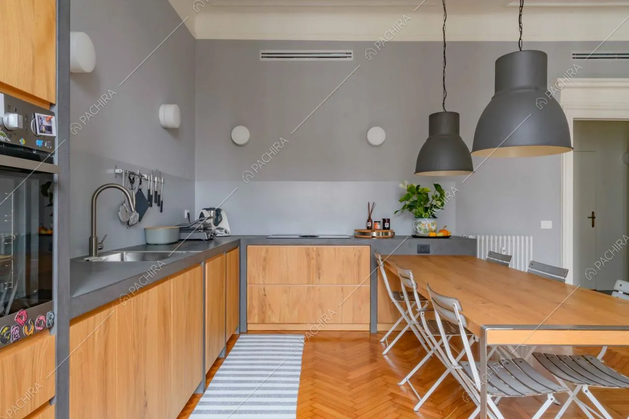 Cucina a parete dalle pareti grigie con fornelli a induzione e tavolo da pranzo in legno