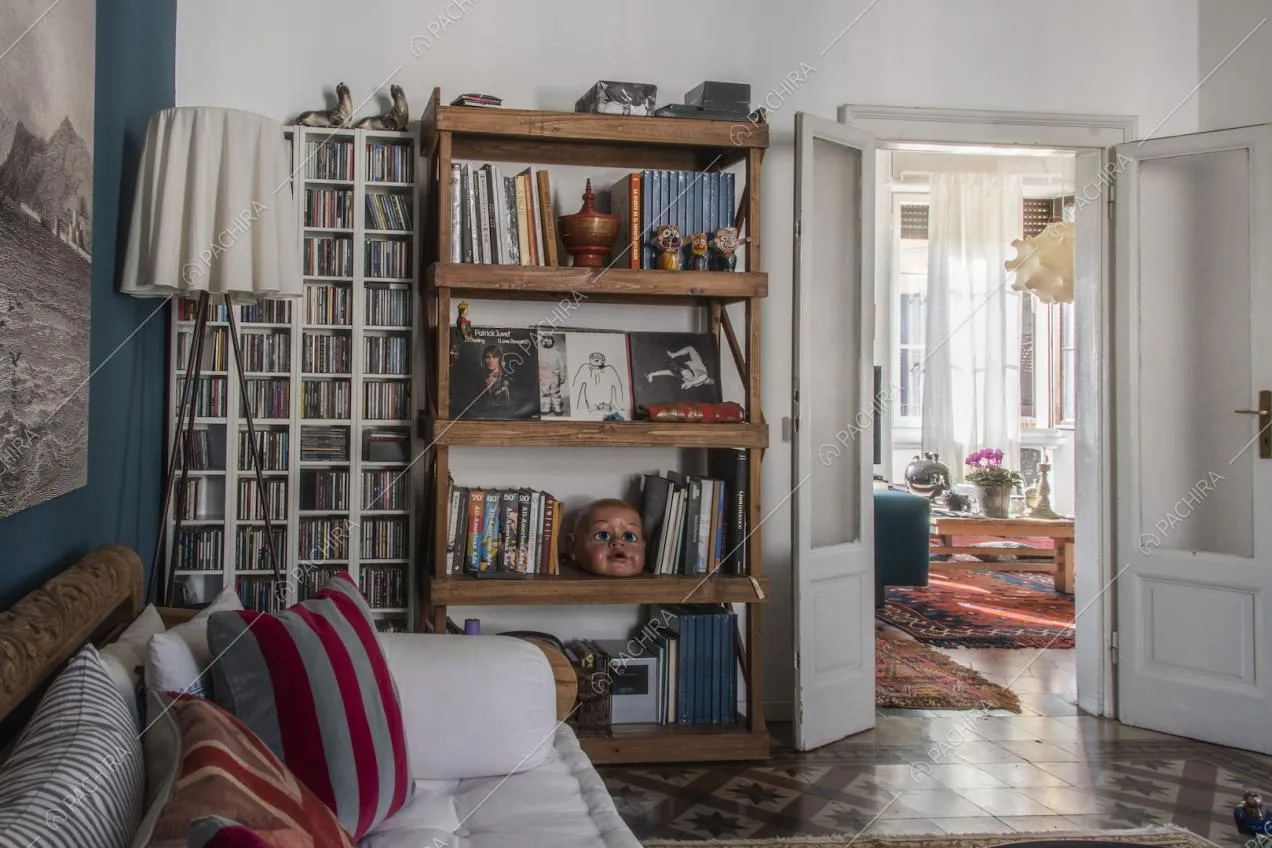 Scaffale in legno pieno di libri, porta d'epoca con affaccio sul salotto