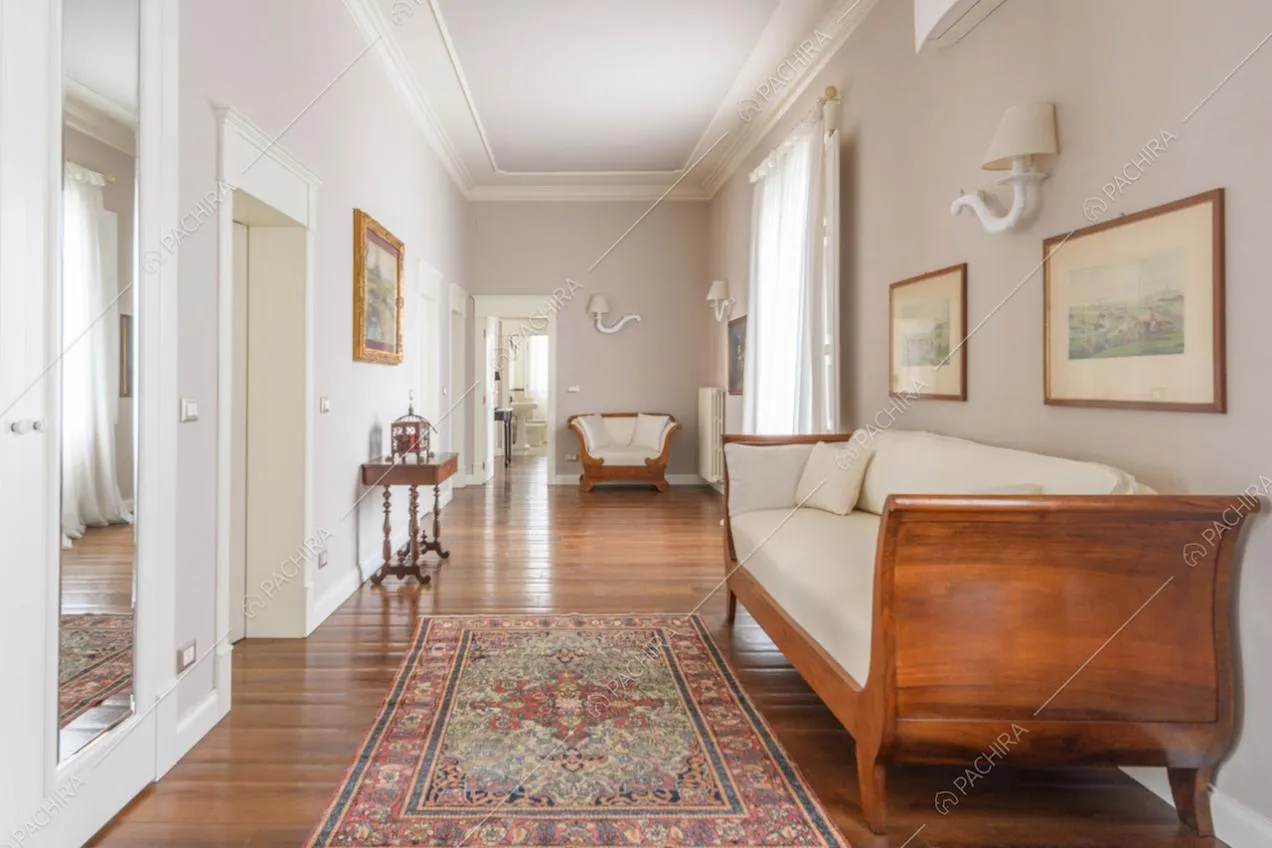 Divani bianchi con struttura in legno nel luminoso corridoio con pavimento in parquet