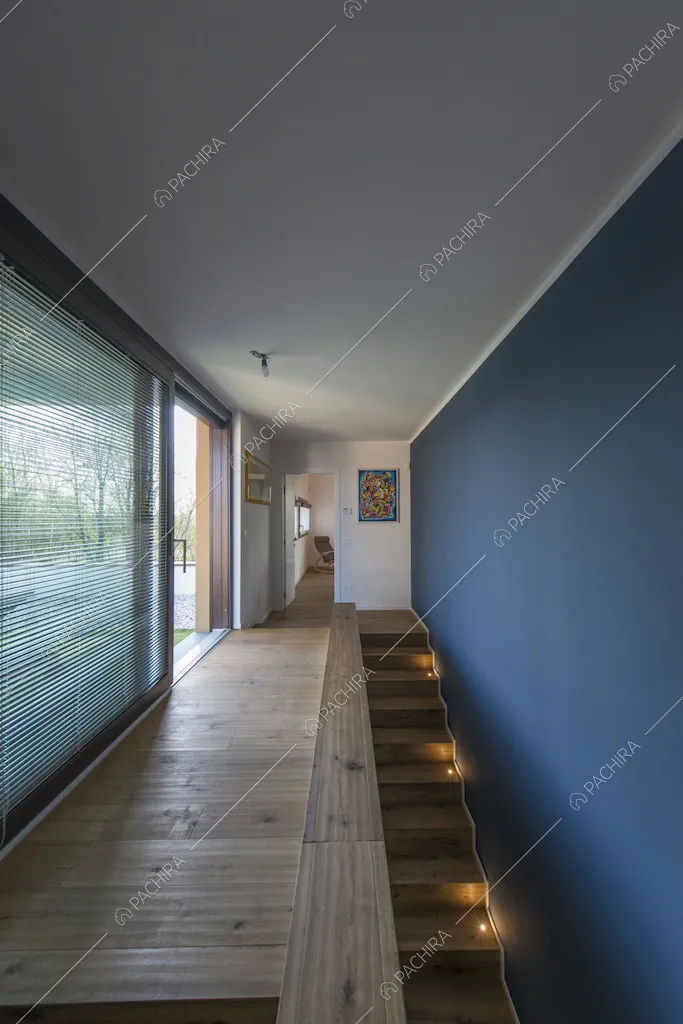 Corridoio con porte-finestre scorrevoli, parete blu e scale in legno