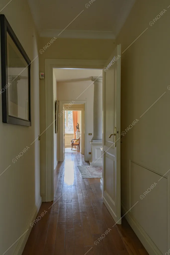 Lungo corridoio con porte e pareti bianche e parquet